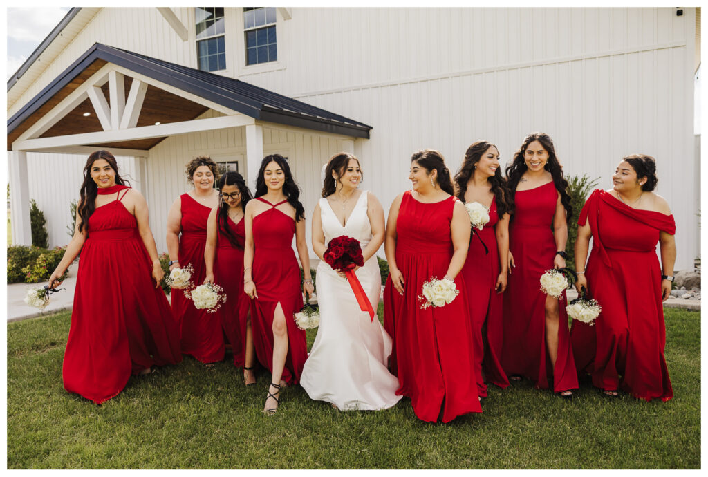 Bride share a candid moment with her bridesmaids walking across the venue lawn