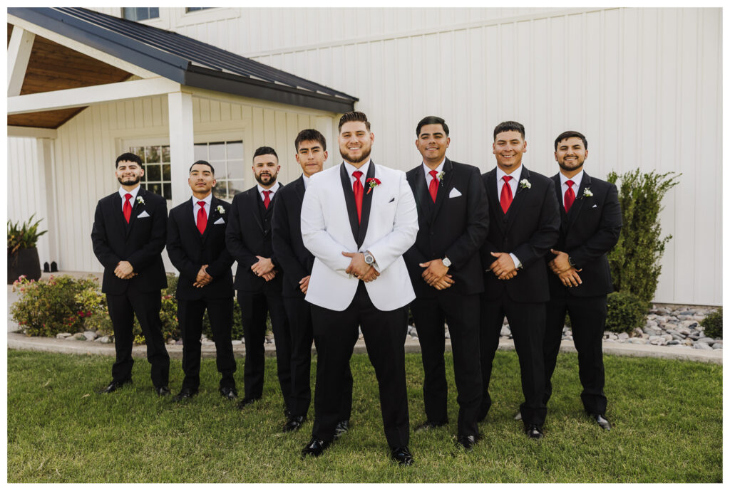 Groom stands with his groomsmen in triangle formation with hands folded like gentlemen