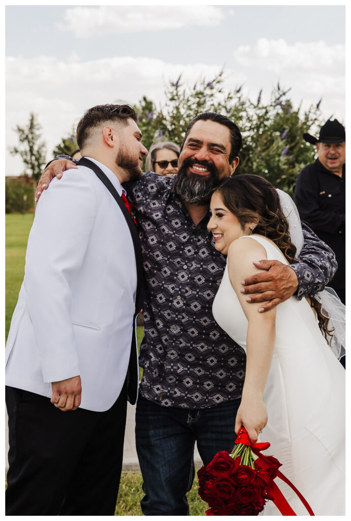 Bride and groom in a congratulatory hug with wedding party guest in Seminole, TX
