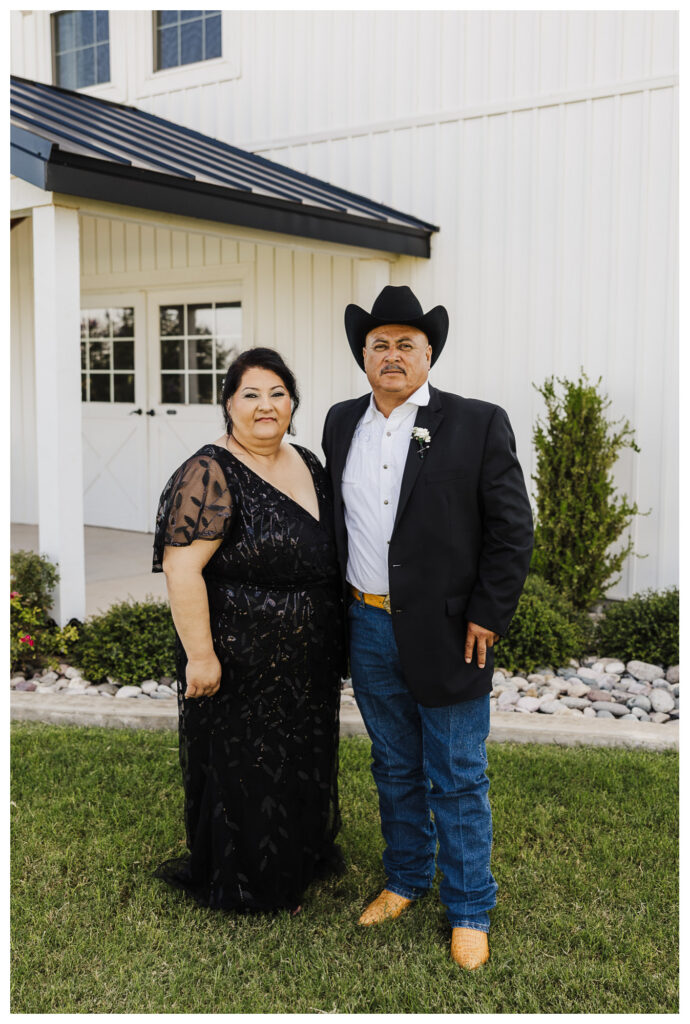 Parents stand in front of the white venue hall dressed in black 