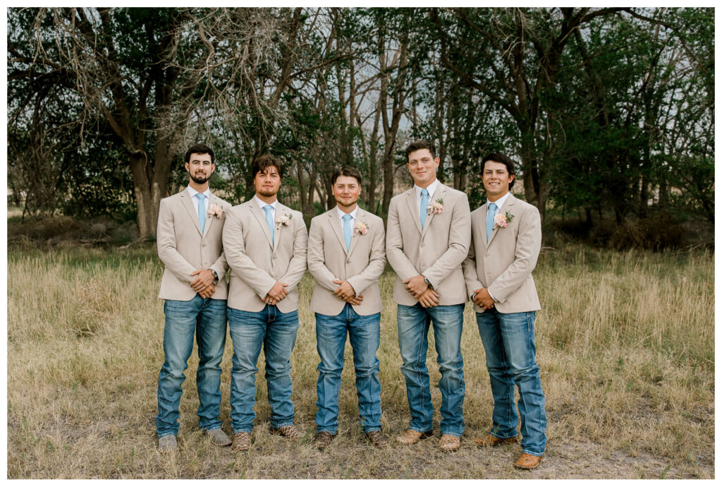 Groomsmen wearing tan suits with light blue ties and blush boutonnieres, showing how wedding colors coordinate with attire